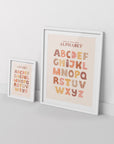 2 framed alphabet posters in boho style, leaning against white wall